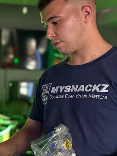 Merwan Unvar von MYSNACKZ befüllt einen Snackautomaten bei einem Kunden